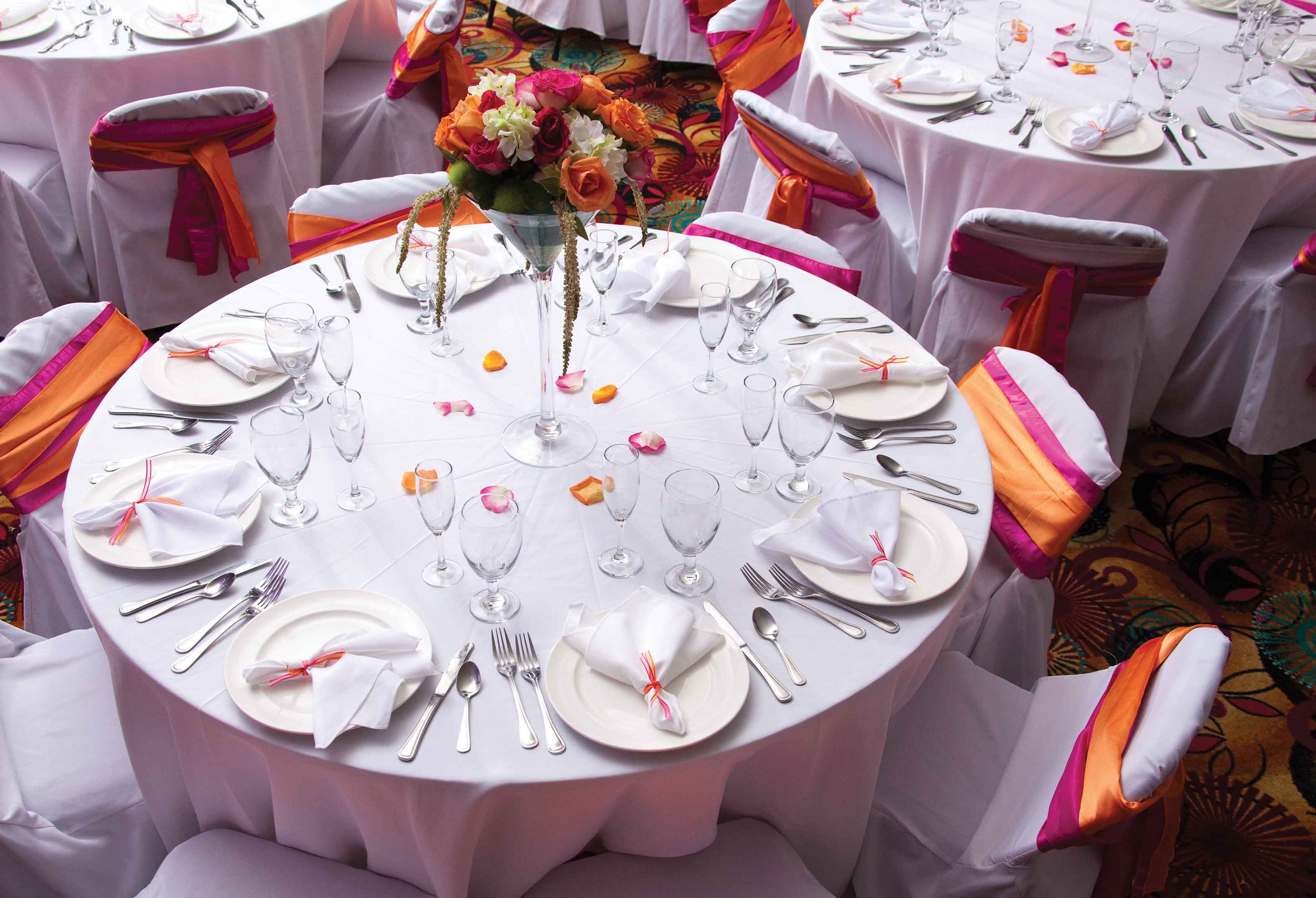 Purple place settings with colorful flower bouquet in the center and white linen