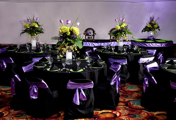 Purple and black place settings on round banquet table with yellow flower arrangement