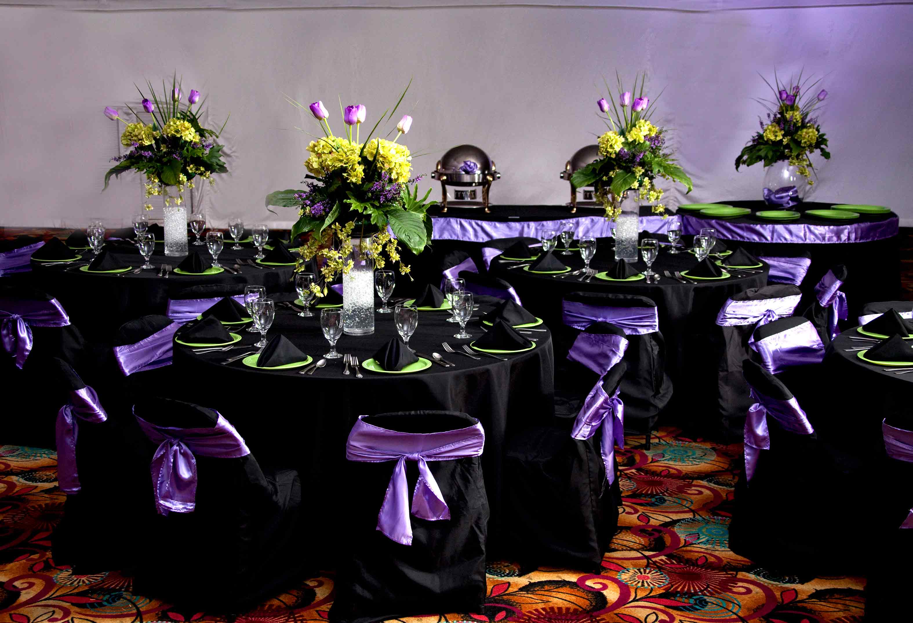 Purple and black place settings on round banquet table with yellow flower arrangement
