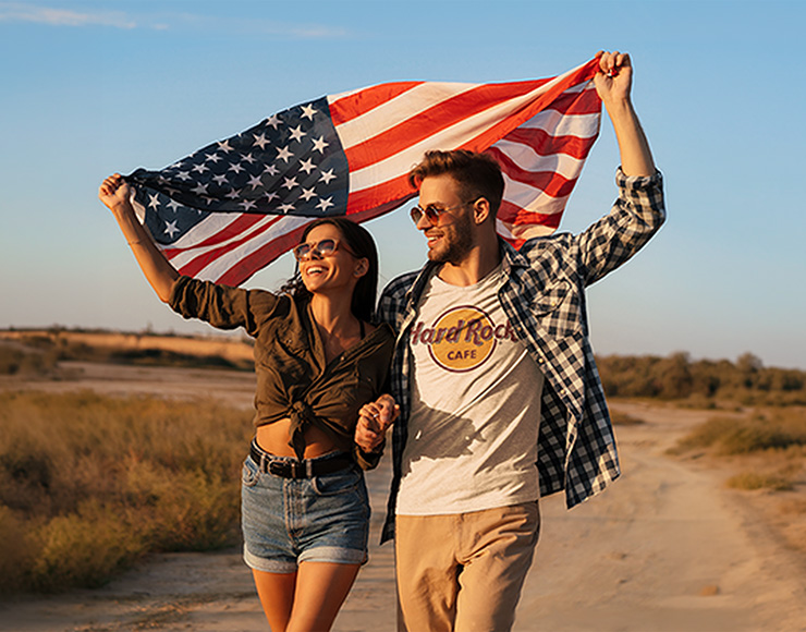 Man and women holding USA flag in Hard Rock classic tee.